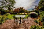 A table for four overlooks the soft green grass yoga patch space. Enjoy cooking and a favorite glass of wine in a special nook of the property.